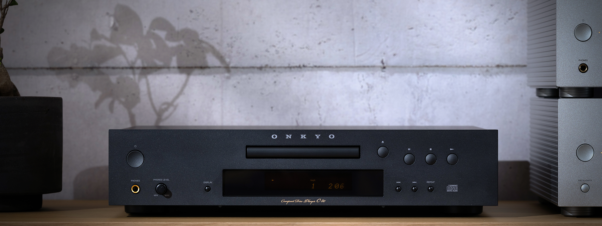 Onkyo Icon C 30 on wood shelving beside Onkyo Icon Series preamplifier and amplifier and small bonsai tree against textured wall 2000x750