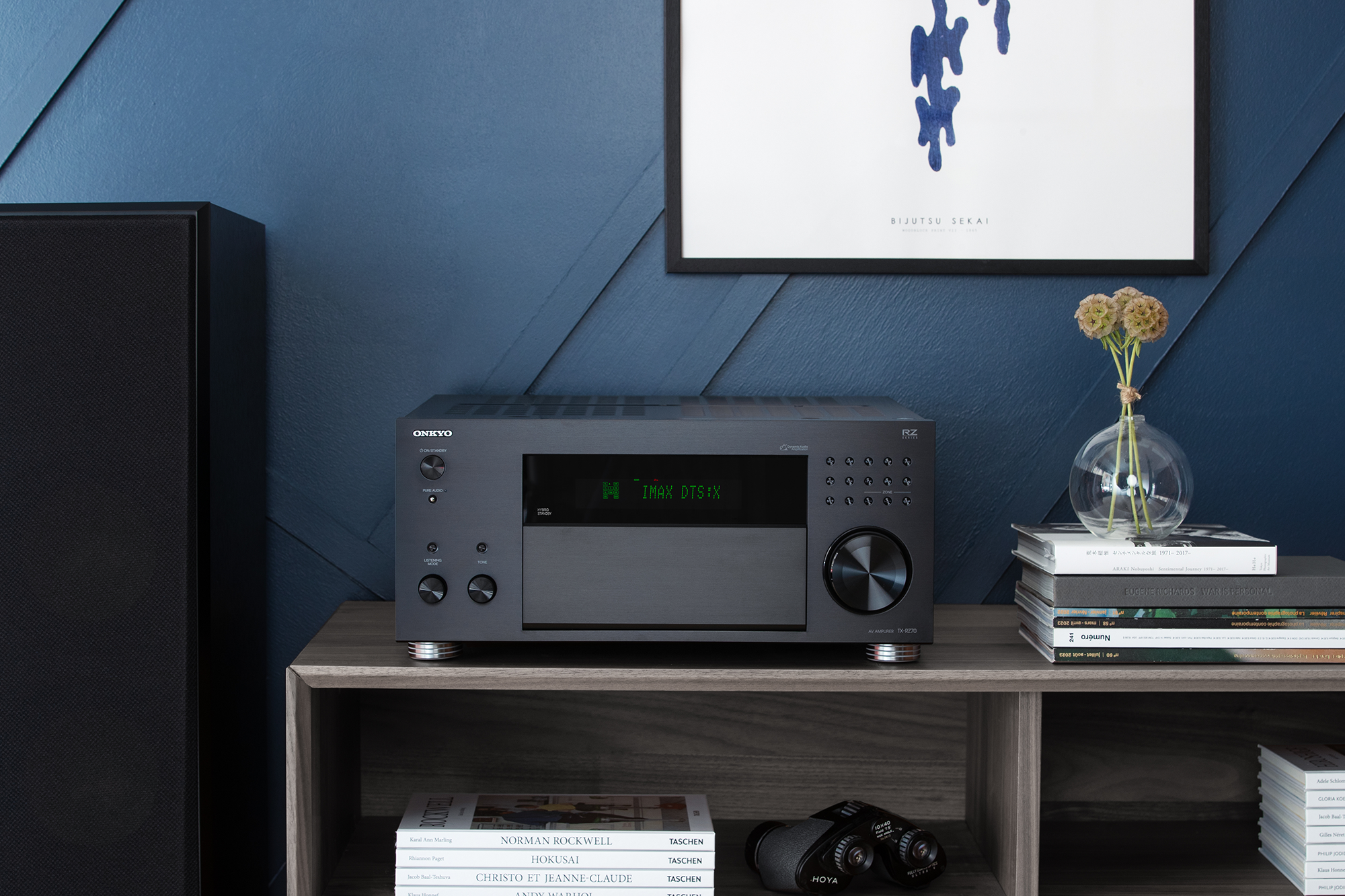 Onkyo TX RZ70 on media console beside floorstanding speakers and stack of books 2000x1333