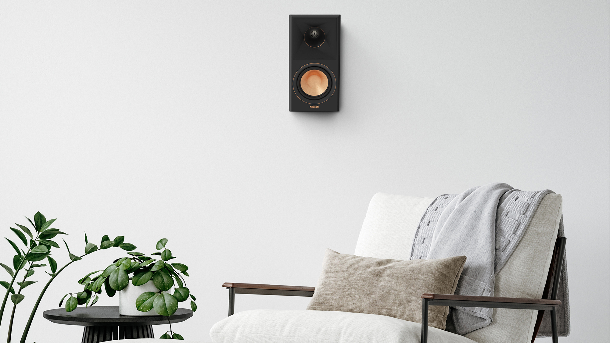 RP 500 SA II surround speaker hung on a greyish white wall near a chair